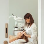 beautician making facial beauty procedures for woman in salon
